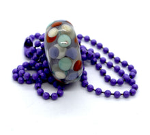 Load image into Gallery viewer, Purple core with orange, purple and light blue encased in clear glass bead on ball chain